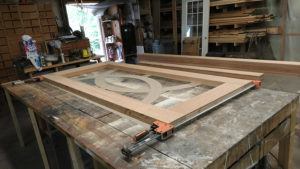 Custom door frame on the (flat) workbench, glued and clamped, with curve patterns laid out.
